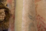 Hand-knotted vintage Oushak rug fragment pillow showing soft pink pile and olive fabric side.