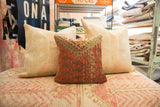 Close-up of vintage Mir Serbend pillow; worn red and blue geometric pattern, visible foundation.