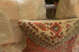 Antique rug fragment pillow corner, featuring terracotta, tan, and dark geometric motifs.