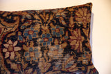 Angled close-up of vintage Kerman fragment pillow, with worn pile, visible foundation, muted blue, red, tan.