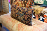 Pillow detail of antique Kerman rug fragment with time-softened indigo, maroon, and beige motifs.