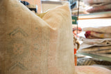 Vintage Oushak rug fragment pillow with faded beige hand-knotted pile and subtle blue details.