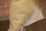 Texture contrast of the hand-knotted Oushak rug remnant and plain beige pillow backing.