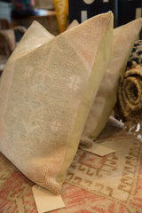 Aged, hand-knotted pile of vintage Turkish Oushak rug fragment pillow in neutral tones.
