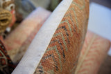 Pillow side: hand-knotted Oushak rug fragment in terracotta and green with woven neutral backing.