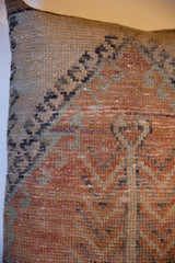 Vintage Oushak rug fragment pillow, showing faded orange, teal, and beige hand-knotted pile.