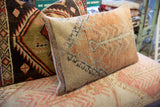 Textured edge of hand-knotted vintage Oushak rug fragment pillow, showing faded peach and blue design.
