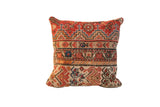 Vintage rug fragment pillow, hand-knotted geometric patterns in brick red, beige, and blue.