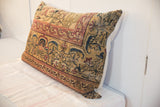 Lower right corner of the Kerman rug pillow, revealing aged golden, red, and blue motifs.