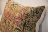 Antique Persian Kerman rug pillow showing faded gold, rust, and indigo mythological figures.