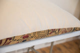 Edge view of oversized pillow, off-white fabric, and hand-knotted antique Persian pattern.