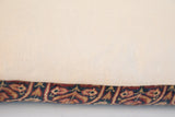 Cream pillow edge with antique Persian Kerman rug fragment in rust and navy.