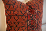 Pillow featuring antique Turkmen rug fragment, highlighting dark geometric motifs on rich russet pile.