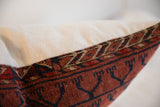 Hand-knotted geometric Turkmen pattern on vintage rug pillow, reddish-brown and dark blue.