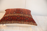 Geometric patterns of a hand-knotted antique Turkmen rug fragment pillow, earthy red tones.