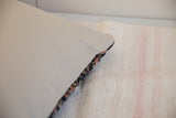 Pillow side view showing a vintage Persian rug fragment with navy, saffron, ivory patterns.