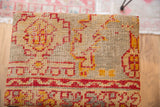 Woven surface of the rug fragment footstool featuring beige, red, and gold geometric patterns.