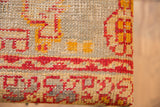 Vintage rug fragment's hand-knotted texture with geometric red and golden pattern.