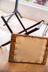 Footstool underside with beige organic muslin, copper nails, and vintage rug fragment side.