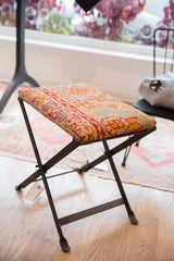 Dark industrial metal frame and legs of the Rug Fragment Footstool.