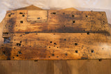 Reclaimed wood tabletop detail with rustic texture, dark patina, and assorted holes.