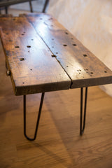Reclaimed wood tabletop detail, showcasing rustic texture, natural holes, and black hairpin leg.
