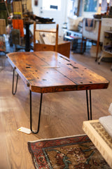 Reclaimed vintage wood coffee table surface with rich grain, visible holes, and rounded edge.