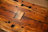 Reclaimed wood coffee table with rustic surface, varied holes, and a lighter wood patch.