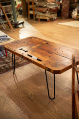 Angled view of reclaimed wood coffee table with a textured top and black hairpin legs.