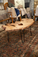 Expressive live edge wood coffee table with natural voids and black hairpin legs.