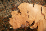 Close-up of expressive live edge wood tabletop, highlighting natural grain and unique knots.