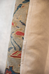 Close-up of side seam connecting antique Persian rug floral vinery to beige linen.