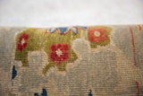 Textured hand-knotted pile of antique Persian rug fragment with red florals, green vines.