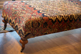 Antique Khorassan Doroksh rug pattern in terracotta, gold, navy, with a turned wood leg.