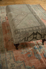 Detail of a curved mahogany finish wooden leg with brass caster wheel.