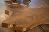 Live edge walnut coffee table with intricate wood grain, natural contours, and rich slab thickness.