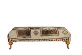 Vintage Oushak rug ottoman coffee table, geometric brown and ivory pattern, with wood legs.