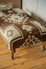 Textured brown and ivory Oushak geometric pattern on ottoman, curved wood leg, brass caster.
