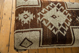 Vintage Turkish Oushak rug fragment on ottoman side, geometric brown and ivory.