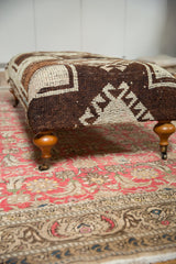 Vintage Oushak rug fragment with geometric brown and ivory pattern, wood leg, and brass caster.