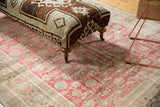 Vintage Oushak rug ottoman with hand-knotted brown, ivory geometric pattern and wood leg.