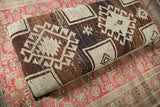 Close-up of textured vintage Oushak rug fragment, geometric brown, charcoal, ivory patterns.