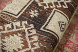 Vintage Oushak rug fragment with geometric brown, ivory, and subtle pink woven pattern.