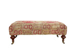 Antique Rug Fragment Ottoman Table with faded red, saffron, ivory Anatolian geometric pattern, mahogany legs.