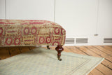 Anatolian rug fragment ottoman side, faded raspberry and ivory geometric pattern, mahogany leg.