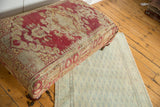 Antique rug fragment ottoman corner, faded red, yellow, ivory distressed pattern, brass caster.