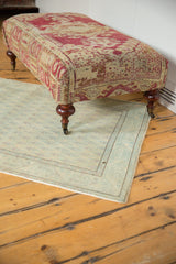 Curved mahogany finished leg with brass caster, showing antique rug fragment upholstery.