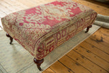 Antique Anatolian fragment on ottoman side, with faded raspberry red and ivory geometric patterns, mahogany leg.