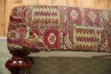 Antique Anatolian rug fragment ottoman corner, faded raspberry, saffron, ivory pattern, mahogany leg.
