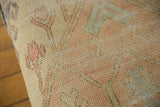 Textured close-up of vintage 1950s Oushak rug fragment in soft pink, pale yellow, and blue.